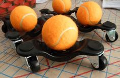 four tennis balls are placed on top of each other in a cart with casters