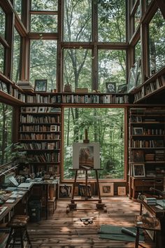 an artist's studio with lots of bookshelves and paintings on the walls