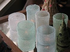 several glass vases are sitting on a table with christmas decorations in front of them