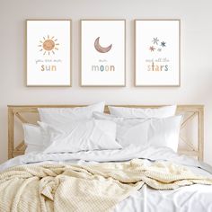 a bed with white sheets and two pictures on the wall above it that say sun moon stars