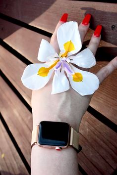 a woman's hand with an apple watch on her wrist and a flower attached to it