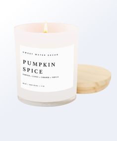 a white pumpkin spice candle sitting on top of a wooden tray next to a wood coaster