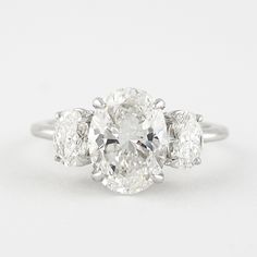 three stone diamond ring in white gold with diamonds on the sides and an oval center stone