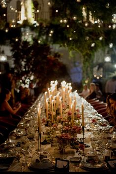 a long table is set with candles and plates for an elegant dinner party in the evening