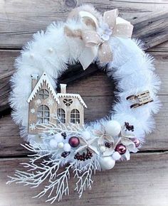 a white wreath with a house and snowflakes hanging on the front of it