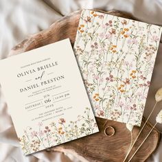 the wedding stationery is laid out on a piece of wood with dried flowers in it