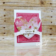 a pink and gold heart shaped card with the word love written on it's side