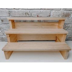 three tiered wooden shelf against a brick wall