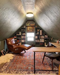 a room with a chair, desk and bookshelf in it's corner