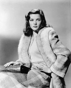 an old black and white photo of a woman wearing a fur coat with her hands on her hips