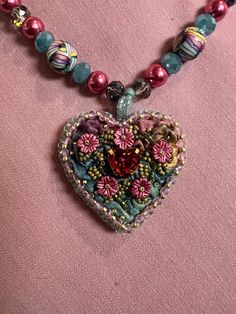 a heart shaped beaded necklace on a pink background