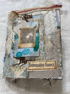 an altered photo is displayed on top of a fabric covered book with a tag attached to it