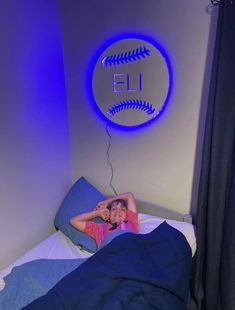 a woman laying in bed with a baseball ball on the wall above her head,