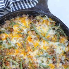 a casserole dish with green beans, sausage and cheese in a cast iron skillet