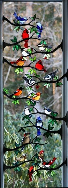 a stained glass window with birds perched on the branches and leaves in front of it