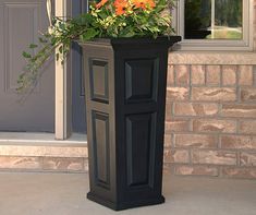 a tall black planter with orange flowers in it