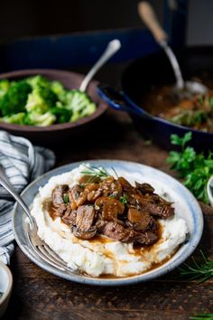 a plate with mashed potatoes, meat and gravy next to other dishes