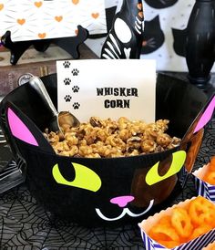 a black cat bowl filled with cereal next to halloween decorations and candy bar wrappers