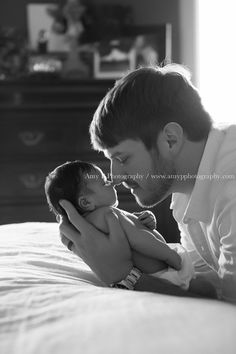 a man holding a baby while laying on top of a bed