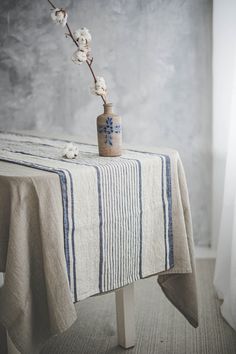 a small vase with flowers in it sitting on top of a wooden table next to a window