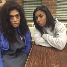 two women sitting at a table with their arms crossed