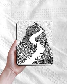 a hand holding up a phone case with an image of a river in the woods