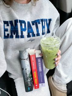 a woman holding a drink and some books