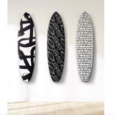 three surfboards are hanging on the wall next to each other in an empty room