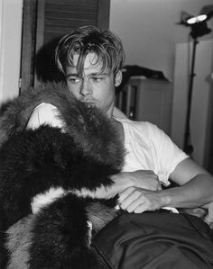 black and white photograph of a man sitting on a couch with fur stole around his neck