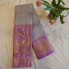 Expertly crafted with 100% pure mulberry silk, this Grey Korvai Kanjeevaram saree is a must-have for any saree connoisseur. Adorned with elegant check patterns and delicate floral buttis, it features a tall lavender peacock border that adds a touch of grandeur. Saree comes with attached running blouse. Pico + Fall service offered as an add-on. Approximate weight: 950 grams All of our saris are silk mark certified handloom saris, made using pure 2g/3g zari and mulberry silk. Note: The colours you Traditional Purple Saree For Formal Occasions, Lavender Wedding Saree With Pallu, Elegant Lavender Saree With Cutdana, Lavender Saree For Wedding And Festivals, Lavender Saree For Wedding And Diwali, Elegant Lavender Saree In Traditional Drape, Lavender Traditional Wear With Self Design For Diwali, Lavender Traditional Wear With Self Design For Wedding, Elegant Lavender Saree For Diwali