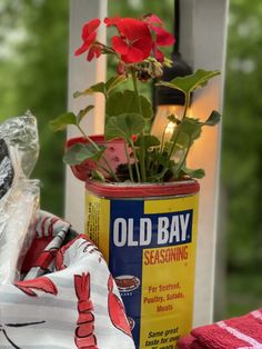 an old bay seasoning can with red flowers in it next to some towels and a candle