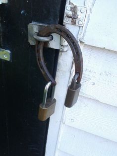 an old metal door handle is attached to the side of a white house with black doors