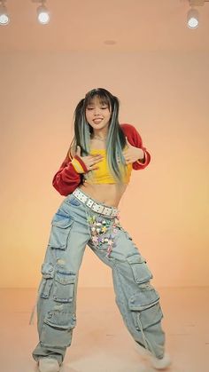 a woman with long hair and jeans is posing in front of a light colored background