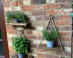 three hanging planters on a brick wall with potted plants attached to the shelves