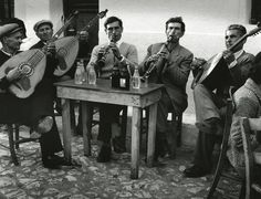 a group of men sitting around a table playing musical instruments