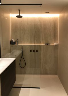 a bathroom with a shower, sink and mirror in the corner is lit by recessed lighting