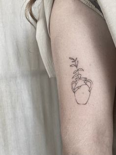 a woman's arm with a small tattoo of a flower in a vase on it