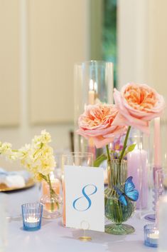 the table is set with candles, flowers and glass vases for an elegant centerpiece