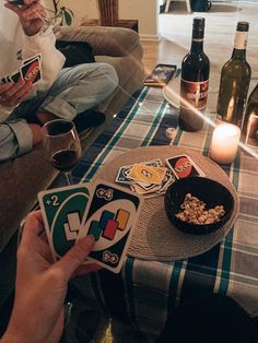 two people sitting on a couch holding up cards and wine bottles in front of them