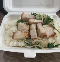 a white takeout container filled with rice and meat on top of it's side