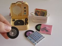 a hand is pointing at an old record player and several other small items on a table