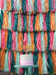 a cake sitting on top of a table next to a wall covered in tassels