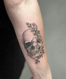 a woman's arm with a skull and flowers tattoo on the left inner forearm