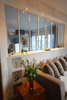 a living room filled with lots of furniture and mirrors on the wall above it's windows