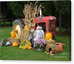 a scarecrow sitting in front of a tractor with hay bales and pumpkins