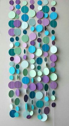 a multicolored paper mobile with circles hanging from it's sides on a wall