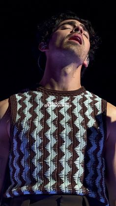 a man with his eyes closed while wearing a knitted shirt and pants, looking up at the sky