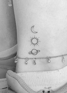 a black and white photo of a woman's ankle with the sun and planets on it