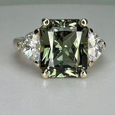 a fancy green and white diamond ring with three diamonds on each side, set in 18k yellow gold