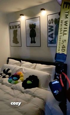 a bed with pillows and stuffed animals on it in a room that has three framed pictures